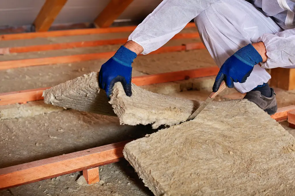 Professional safely removing old attic insulation.