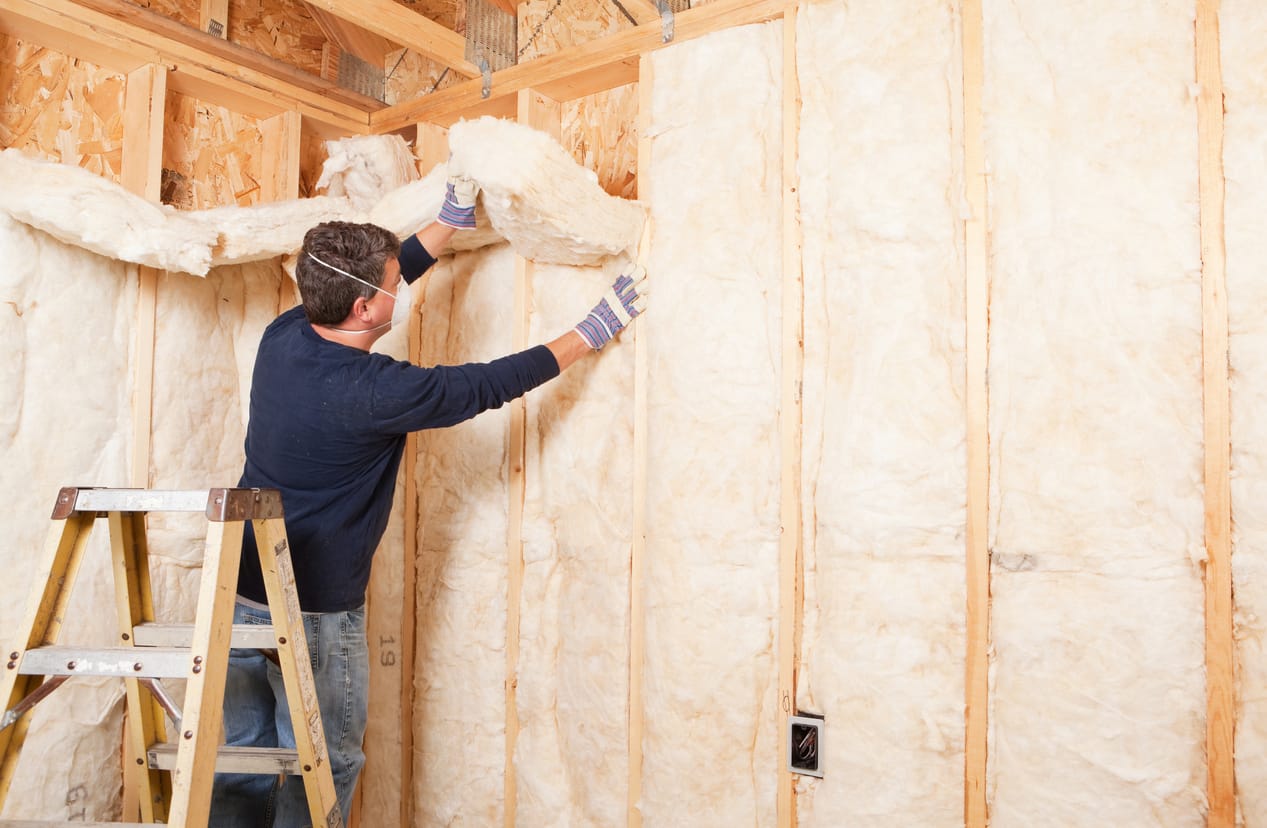 Contractor fitting batt insulation between attic joists