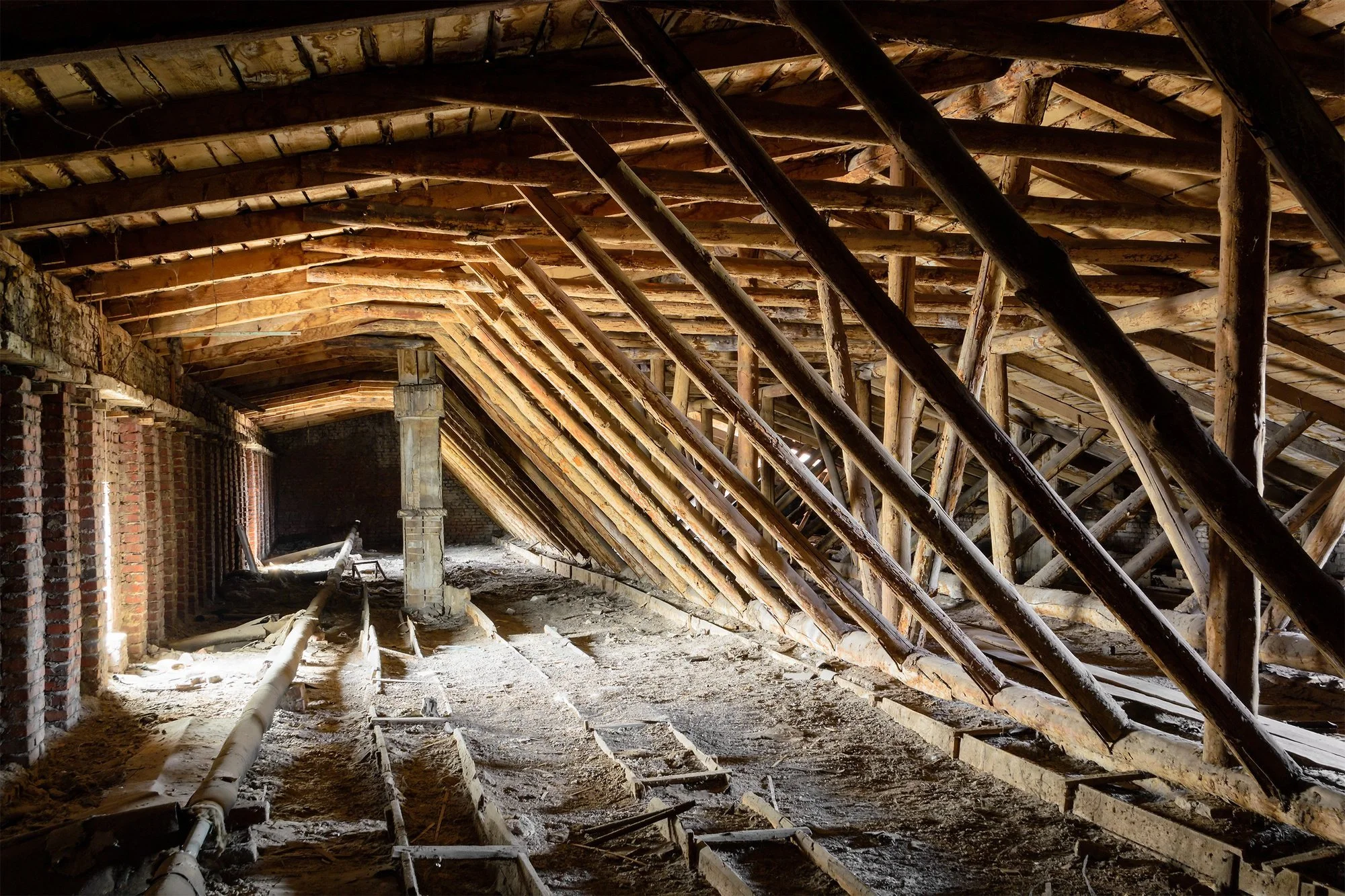 Old timbered loft with exposed beams and worn floorboards.