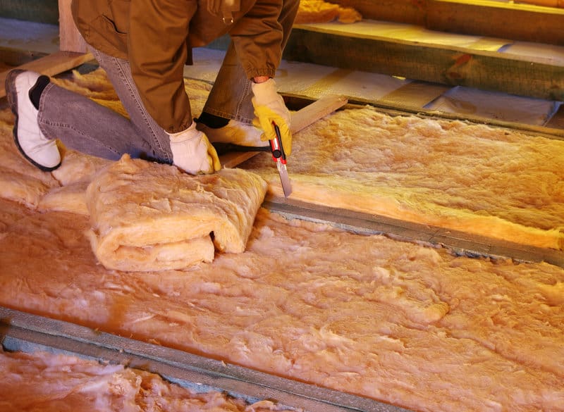 Construction worker thermally insulating house attic with glass wool