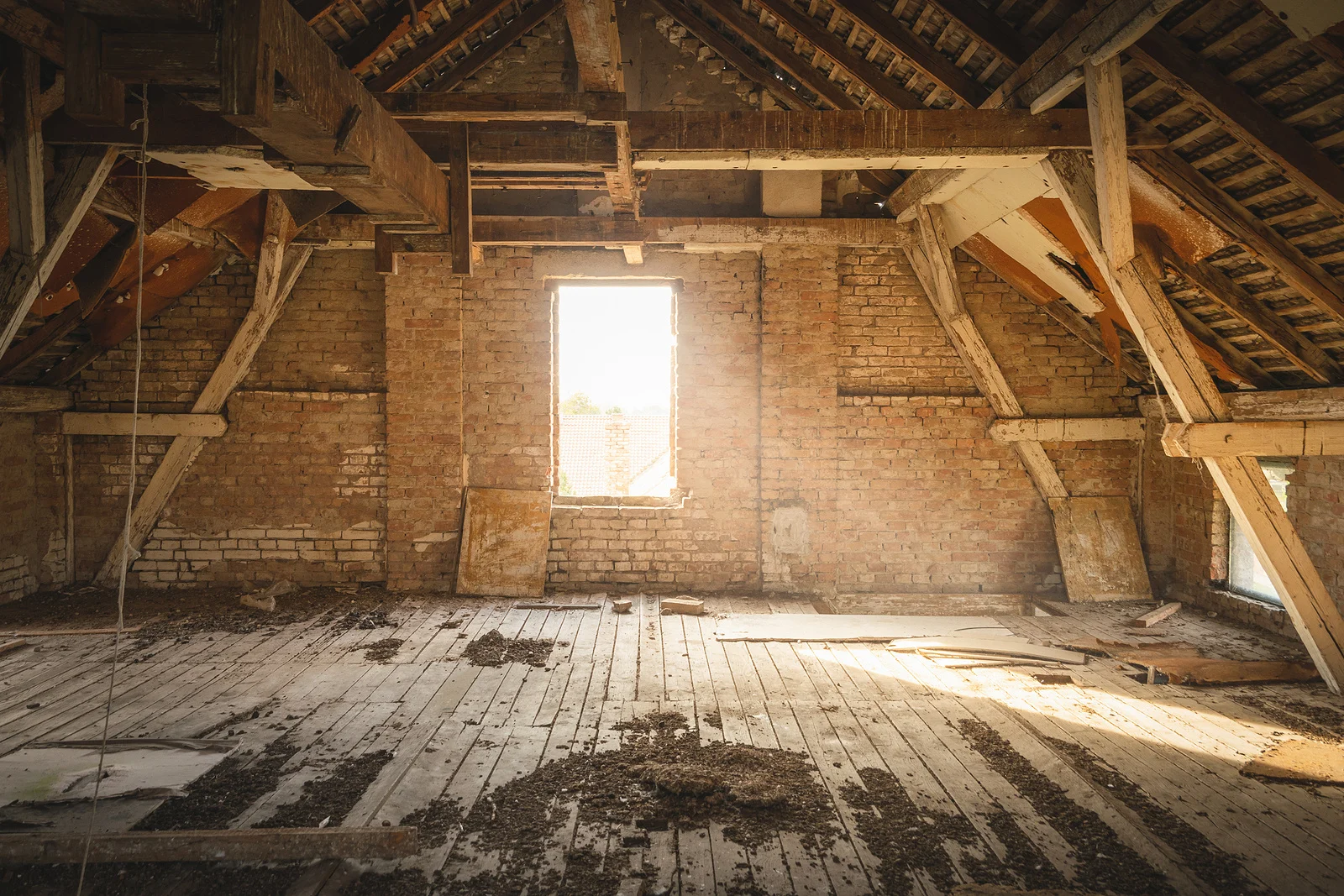 Insulation being installed in an older attic with exposed beams.
