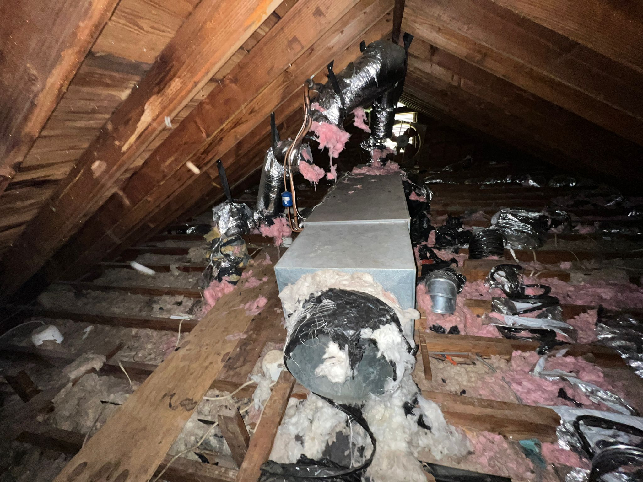 Attic with poorly installed insulation showing gaps and uneven coverage.
