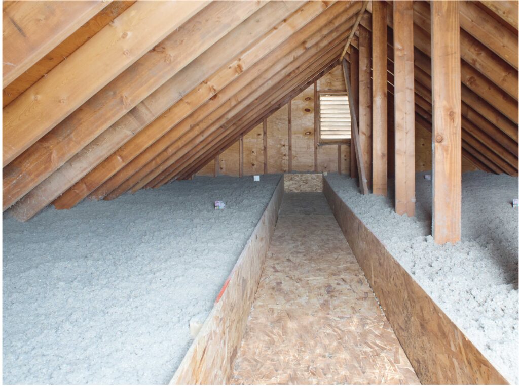 Attic interior with wooden beams and blown-in insulation covering the floor 