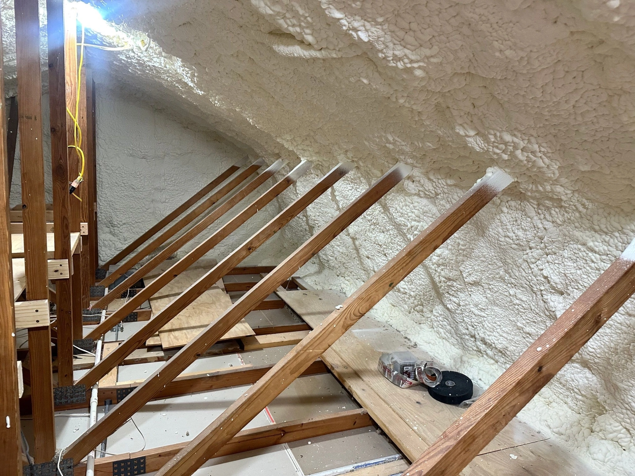 Spray foam insulation installed between attic roof framing to improve home energy efficiency.