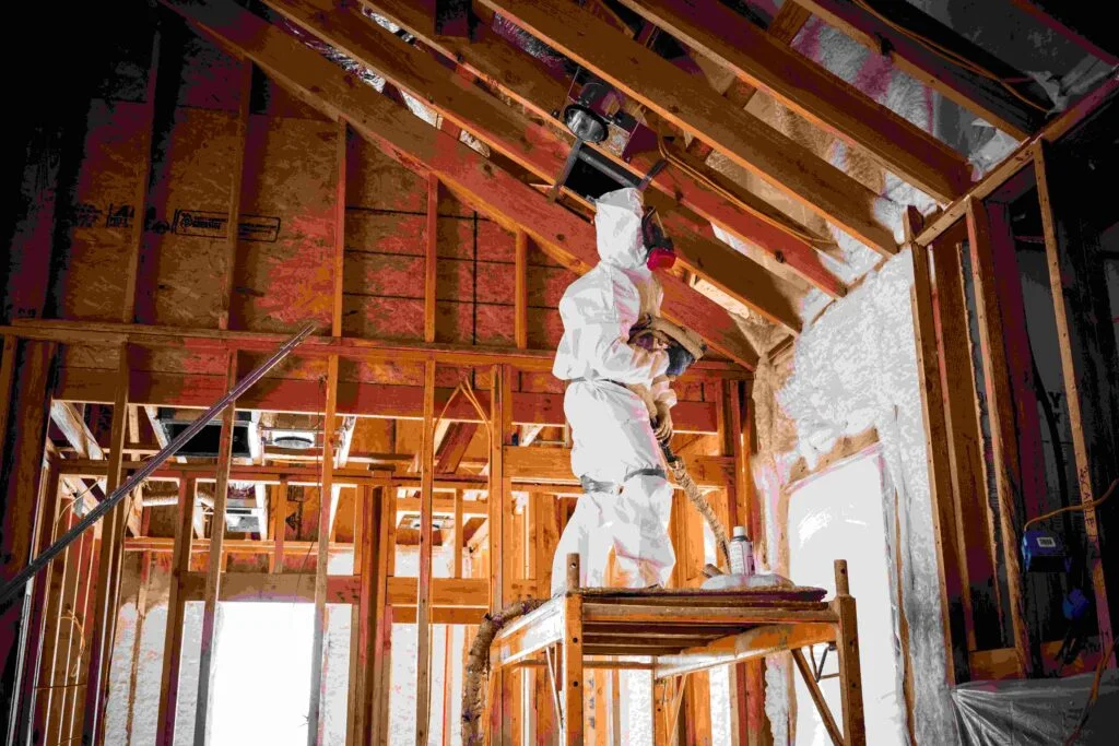 Technician in protective gear installing blown-in attic insulation.
