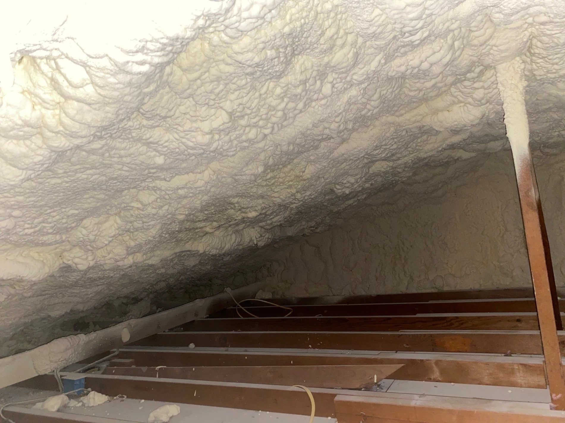 Exposed attic insulation between wooden ceiling joists.